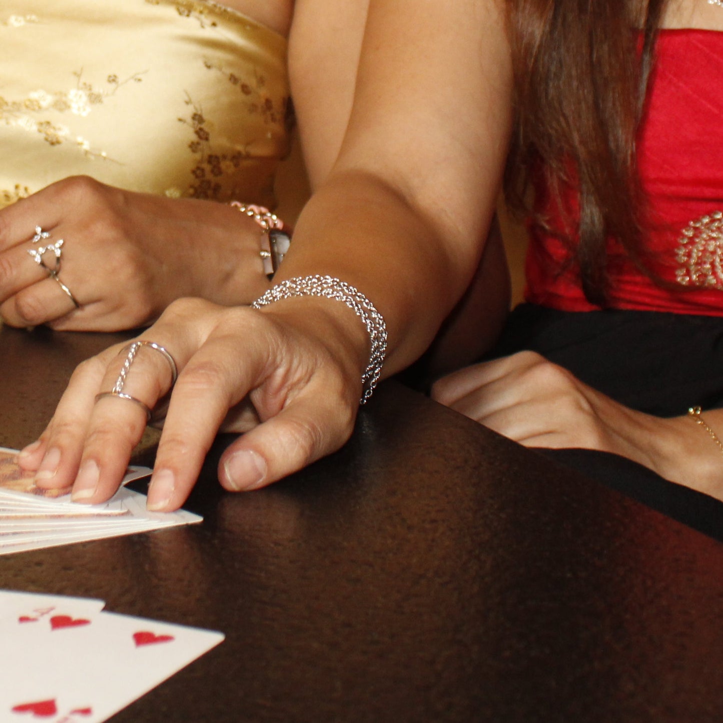 Two women playing cards at a table with a neutral background