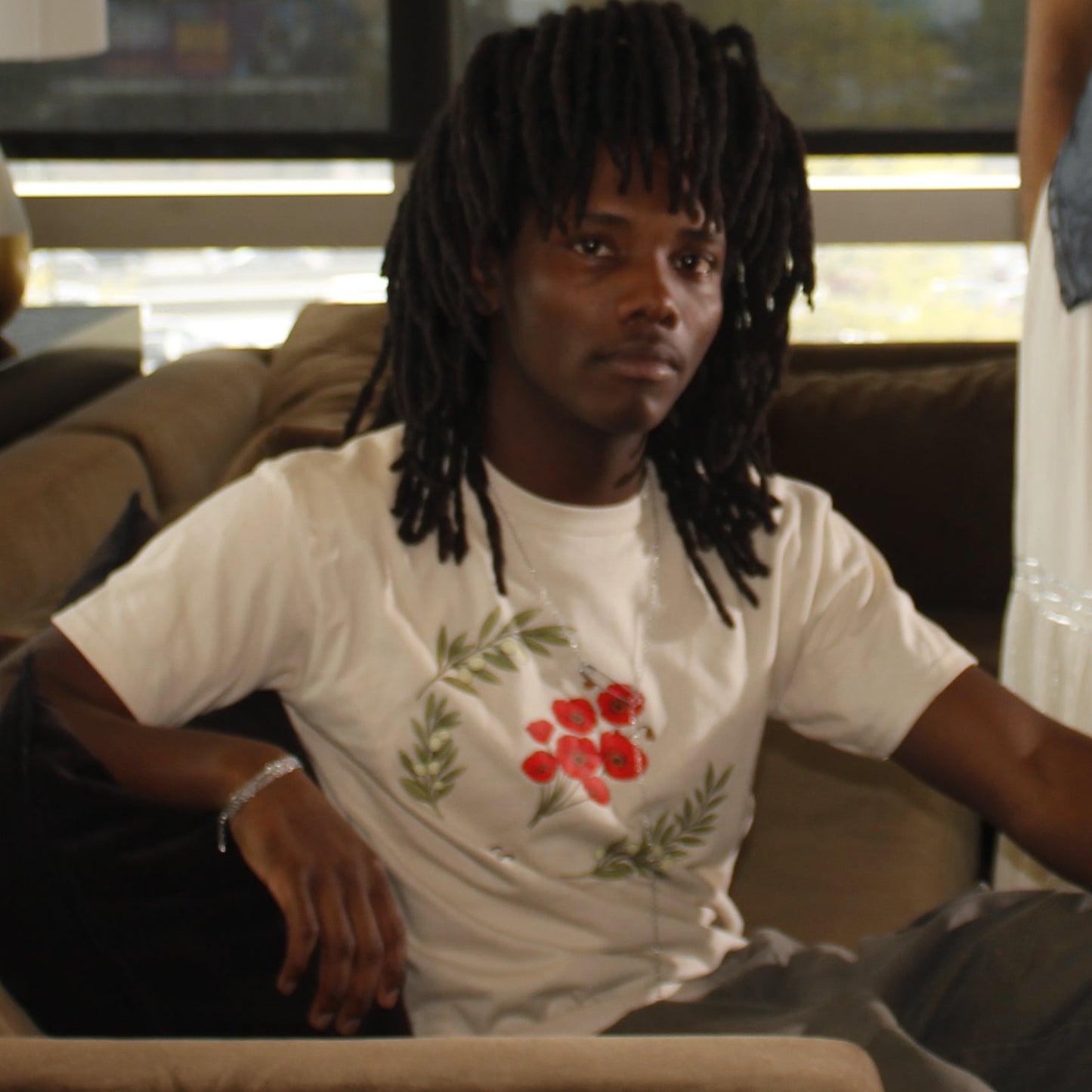 Four individuals sitting on a couch in a modern indoor setting with large windows.