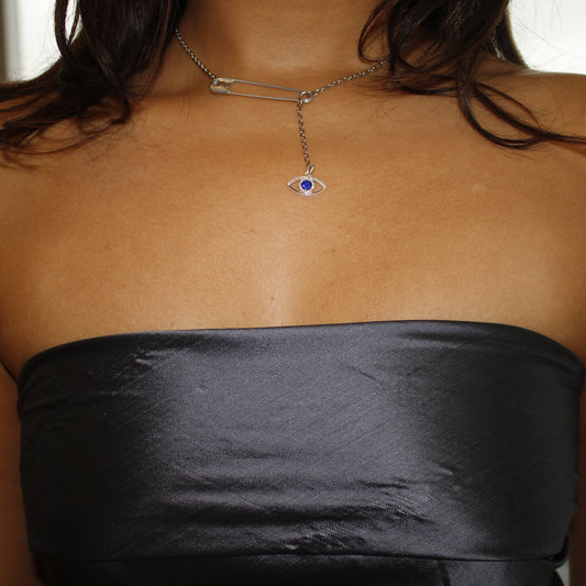 Person wearing a black strapless dress with a necklace featuring an eye symbol.