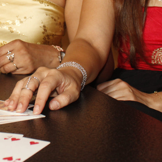 Two women playing cards at a table with a neutral background